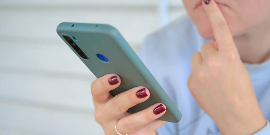 広島でお酒買取店を選ぶためにスマホで口コミや評判をチェックしている様子